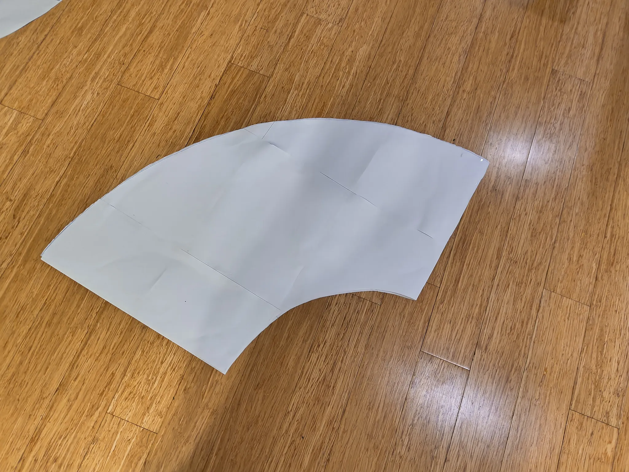 A single curved paper pattern piece on the floor
