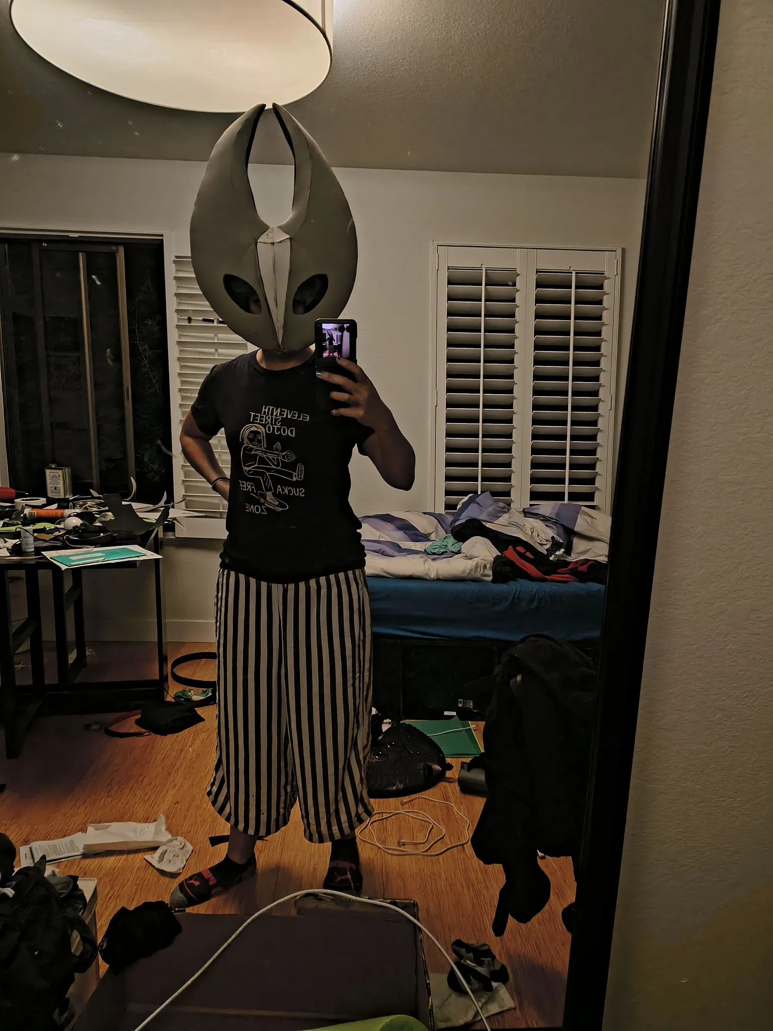 A mirror selfie wearing the raw gray foam mask over a black t-shirt in a messy room, with the diamond cut visible on the front between the horns