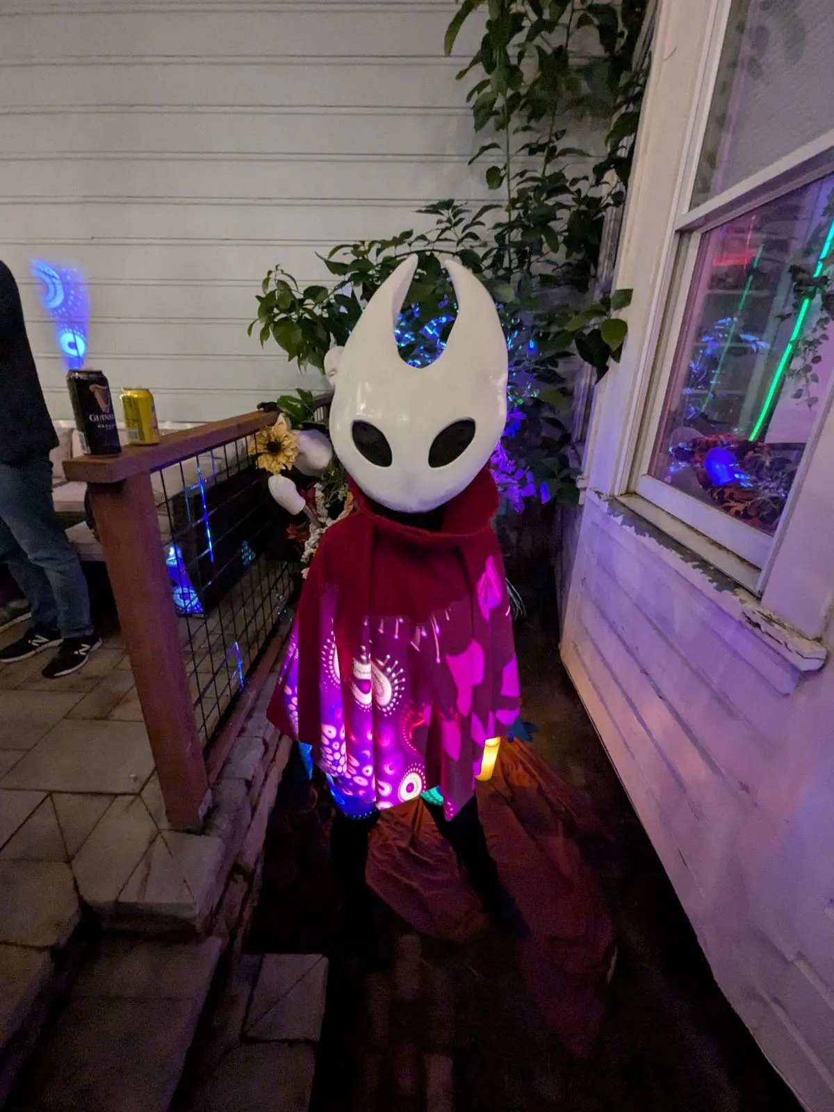 Hornet on a porch at night, the mask glowing under purple lights