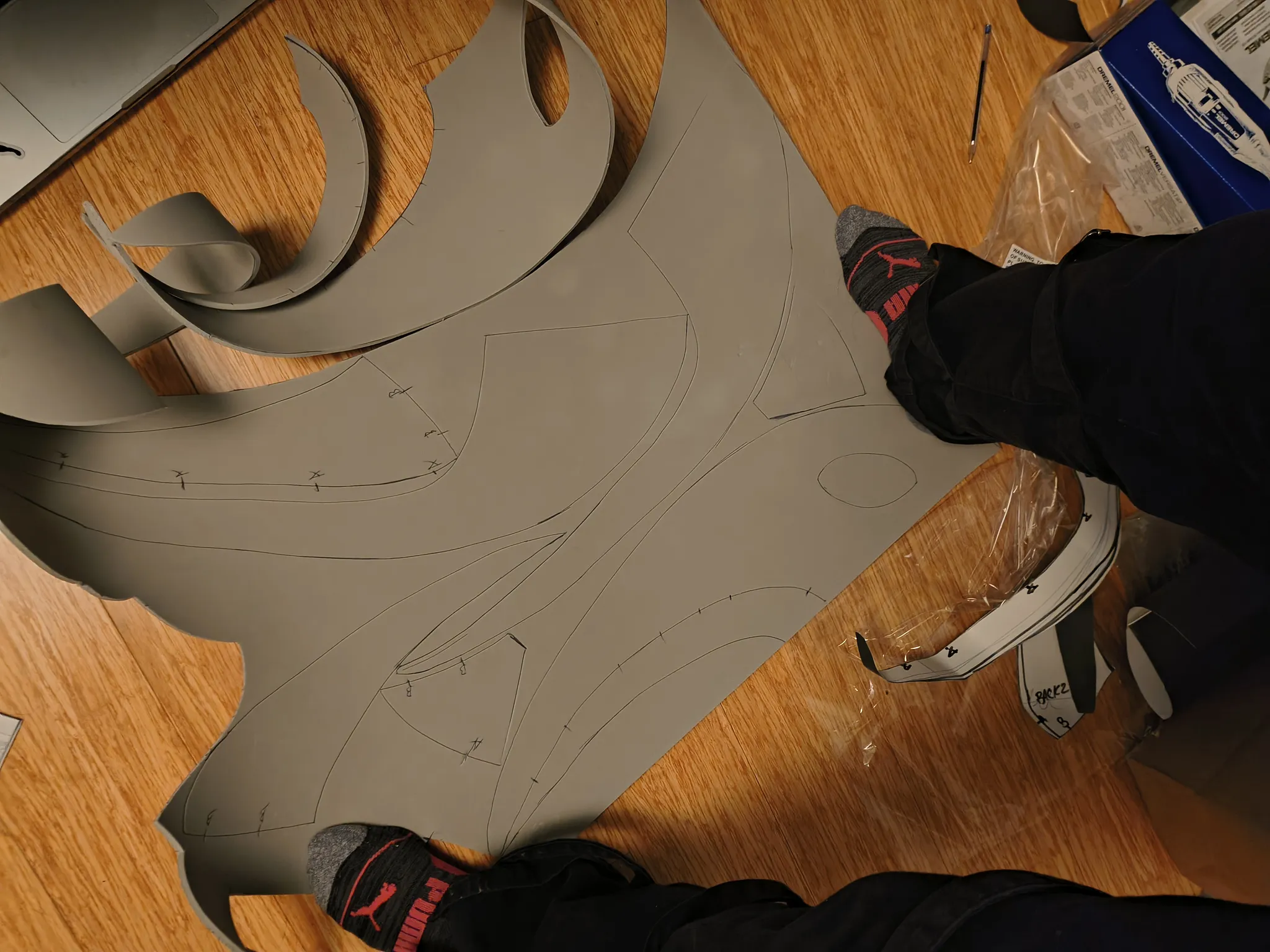 A sheet of gray EVA foam on the floor with the mask pattern drawn and partly cut out