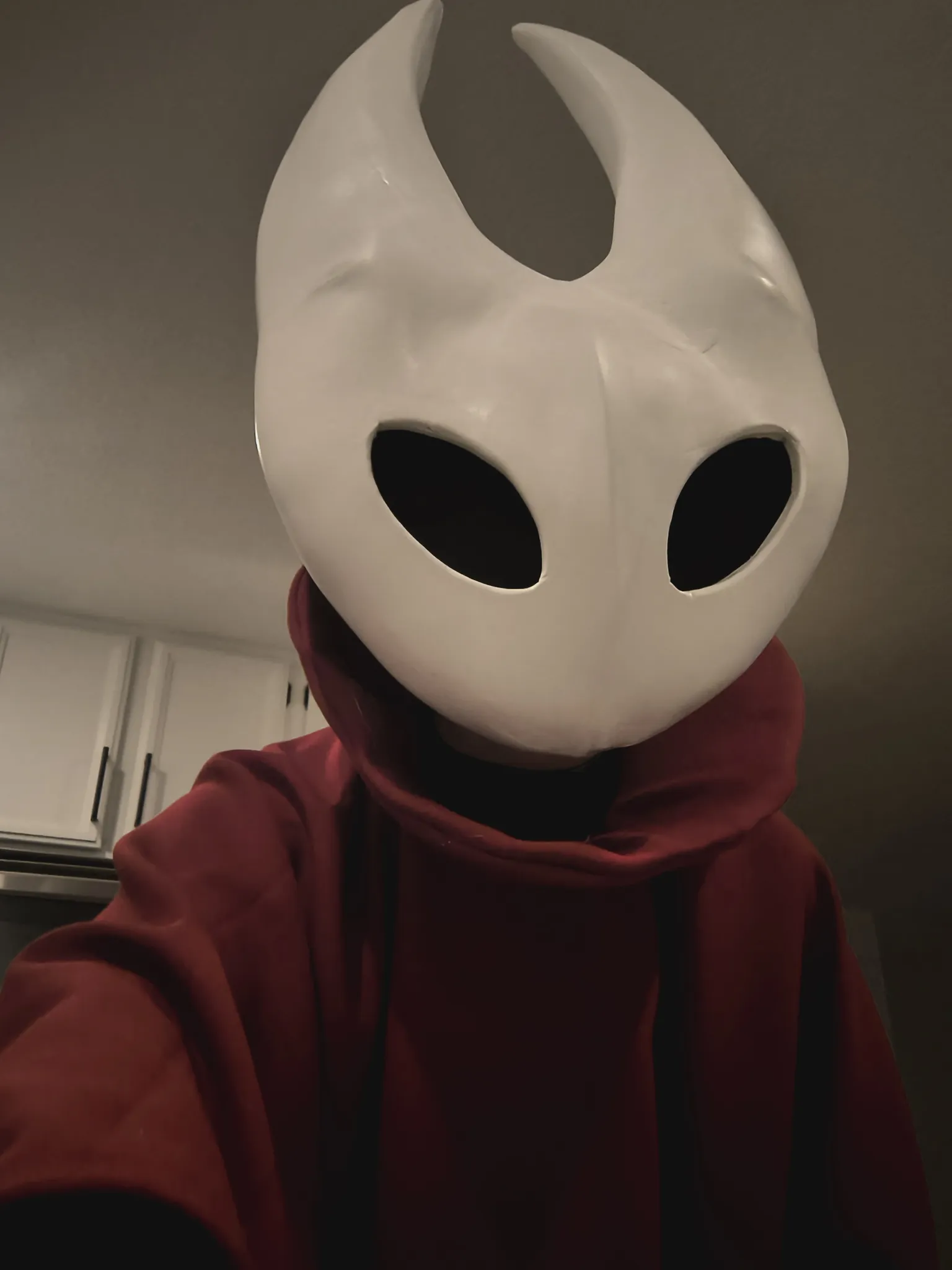 A selfie in the white mask and red cloak, indoors