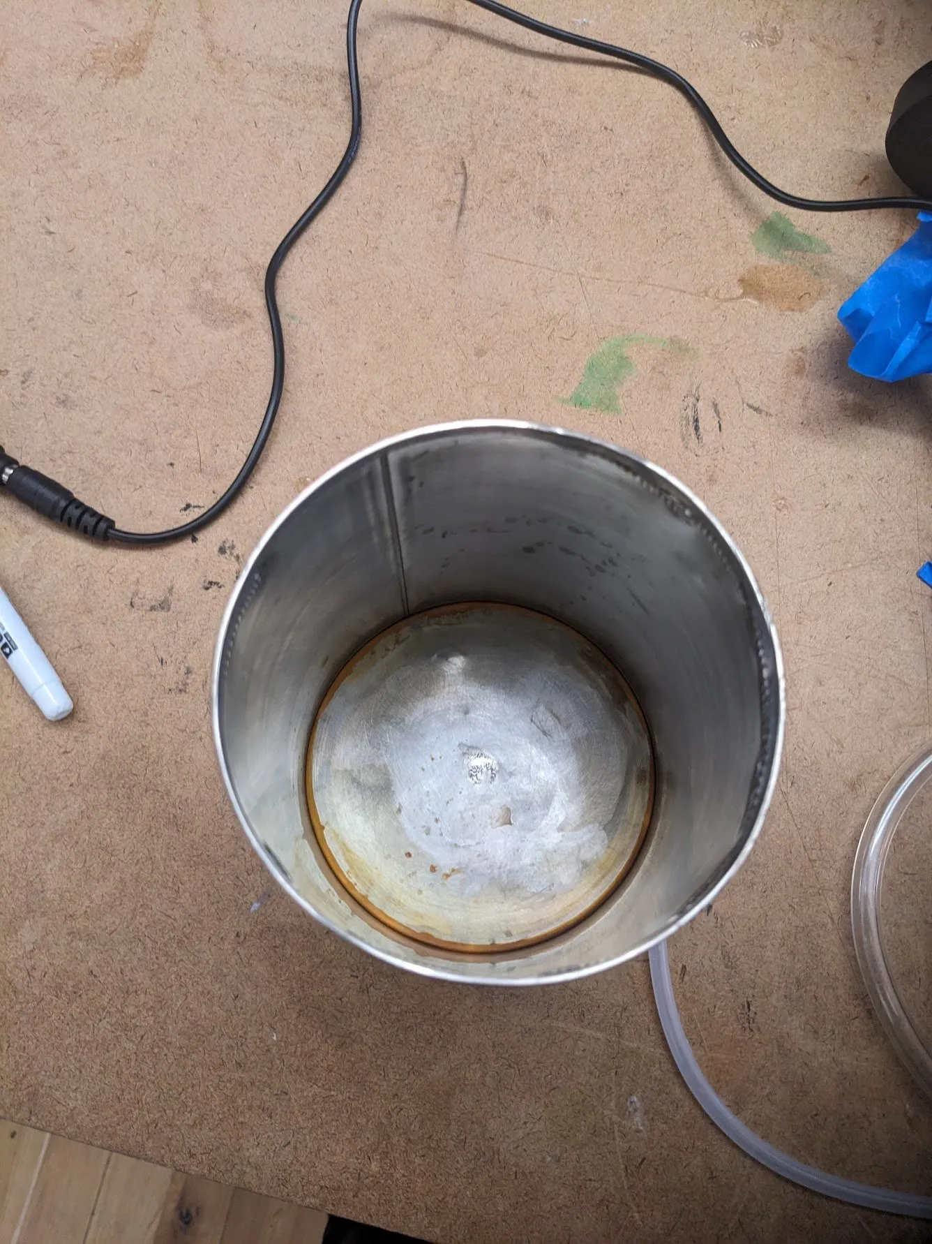 Looking down into the brushed metal bucket, where a large patch of orange rust has bloomed across the bottom after a single day.
