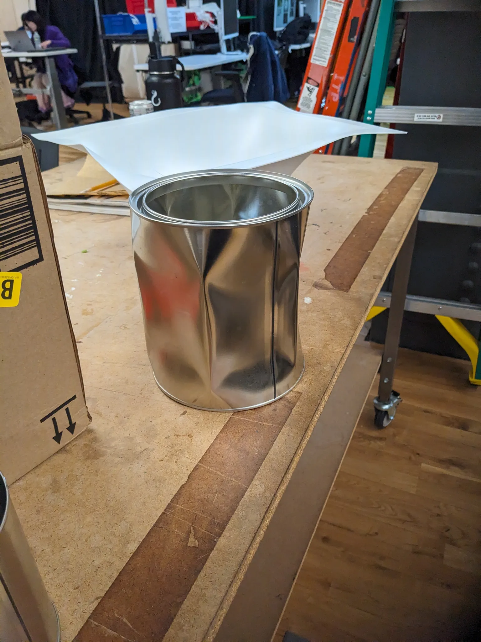 A vacuum formed sheet of white plastic draped over a metal paint can on a workbench, the plastic peeled up at the edges.