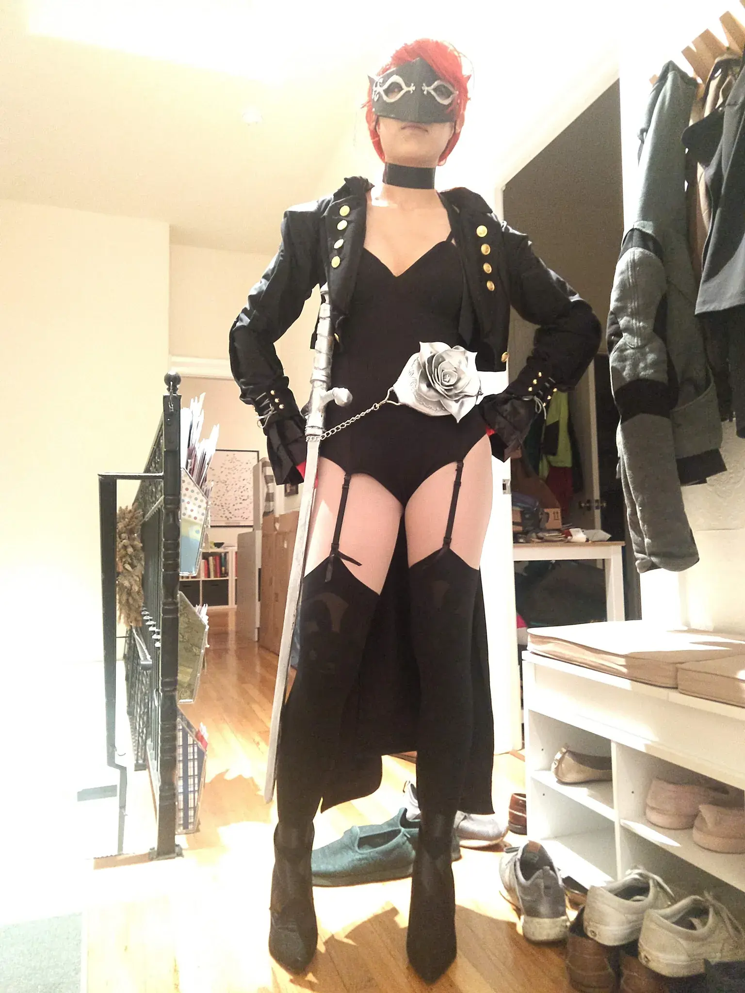Photograph of a girl in a red wig and black leotard and sword standing proudly