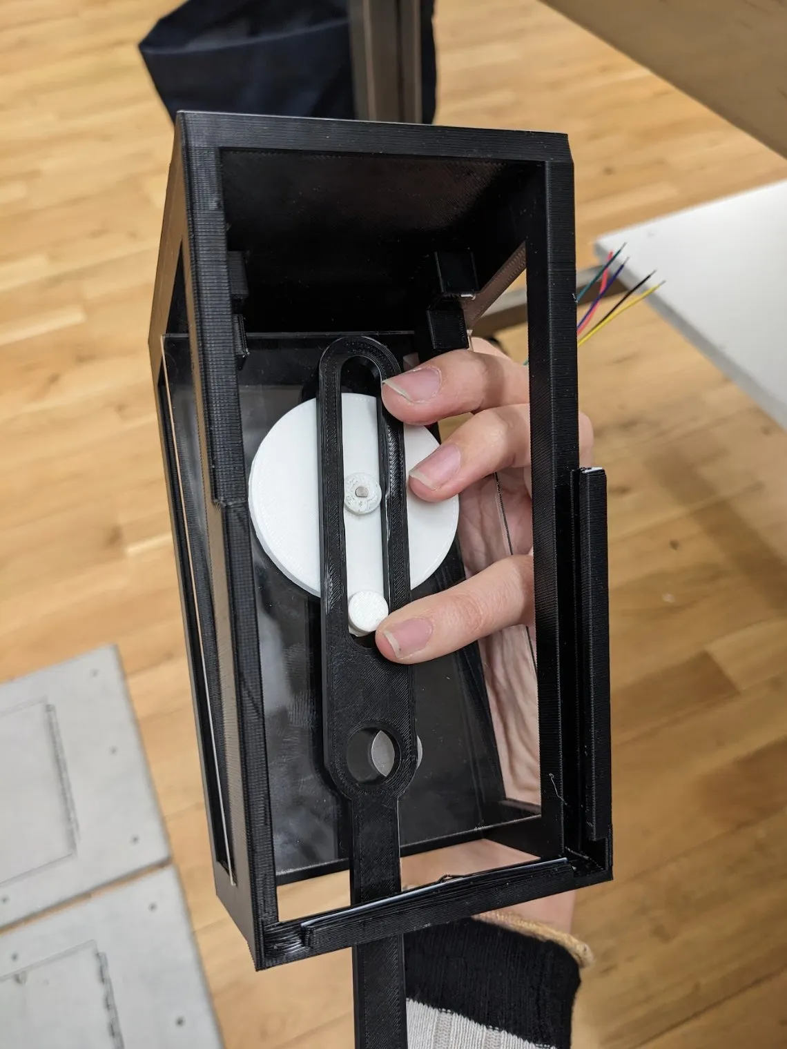 A hand holding the frame with a white circular disc positioned inside it, working out where the motor should mount.