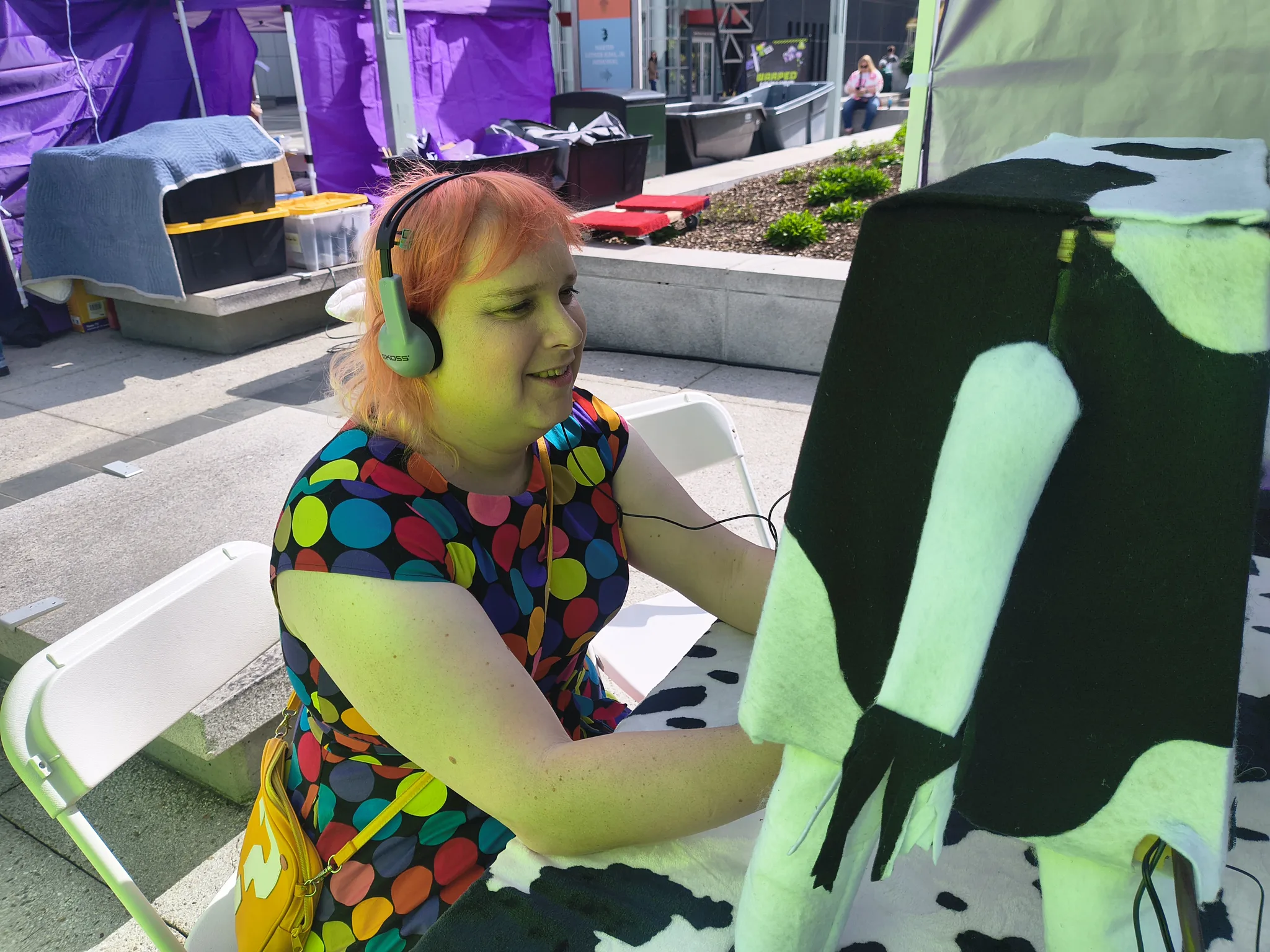 Photograph of a player in headphones squeezing the udder under the Warped Inputs tent